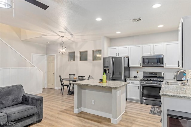 kitchen featuring sink, white cabinetry, stainless steel appliances, and hanging light fixtures