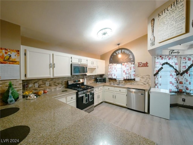 kitchen featuring decorative backsplash, appliances with stainless steel finishes, sink, light hardwood / wood-style flooring, and white cabinets