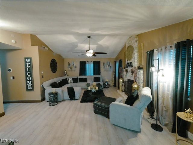 living room with ceiling fan, a large fireplace, lofted ceiling, and light hardwood / wood-style flooring