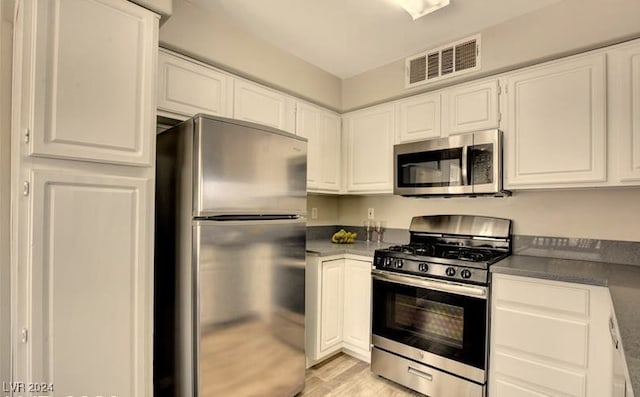 kitchen with white cabinets, appliances with stainless steel finishes, and light hardwood / wood-style flooring