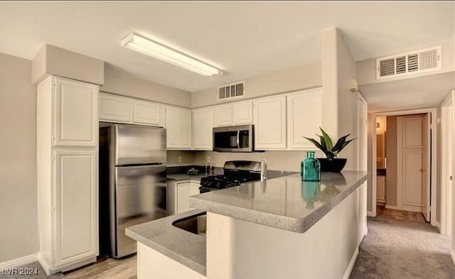 kitchen featuring white cabinets, kitchen peninsula, light carpet, and appliances with stainless steel finishes