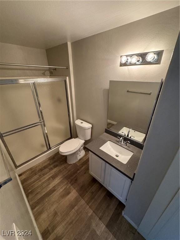 bathroom with hardwood / wood-style floors, vanity, toilet, and walk in shower