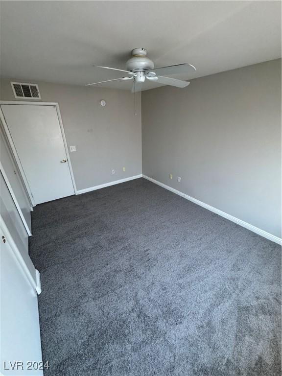 unfurnished room with dark colored carpet and ceiling fan