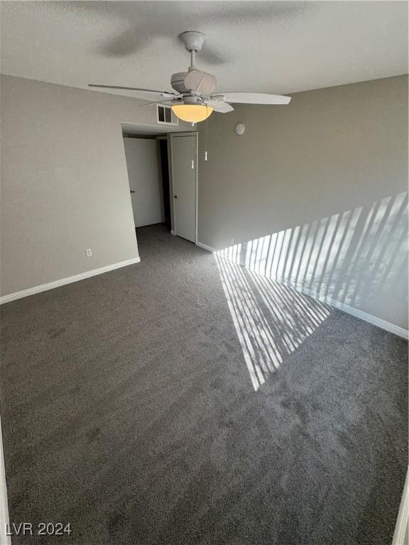 spare room featuring ceiling fan and dark carpet