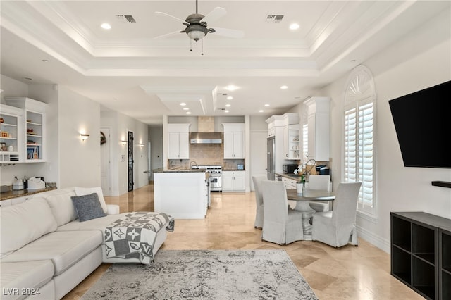 living room with ceiling fan, crown molding, and a tray ceiling