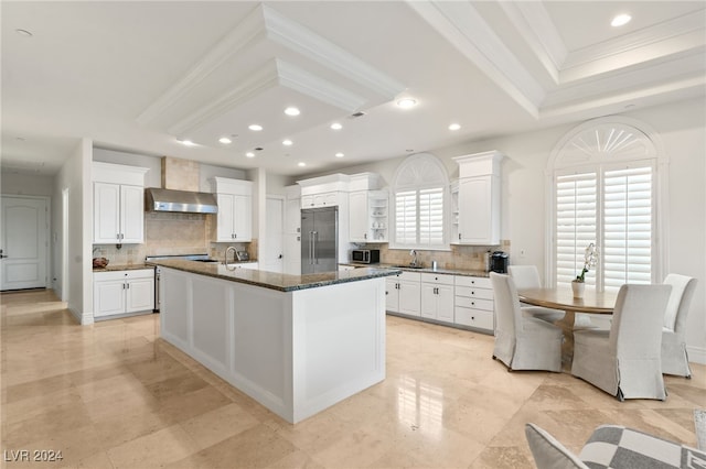 kitchen featuring wall chimney exhaust hood, tasteful backsplash, a kitchen island with sink, and stainless steel appliances