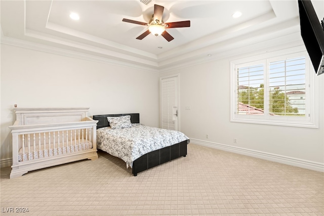 carpeted bedroom with a tray ceiling, ceiling fan, and crown molding