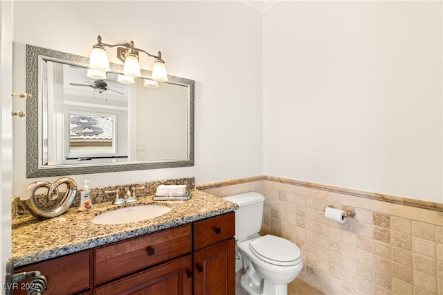 bathroom featuring vanity, ceiling fan, toilet, and tile walls