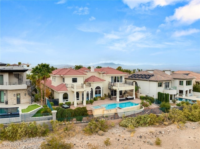 rear view of property featuring a patio area, an in ground hot tub, and a balcony