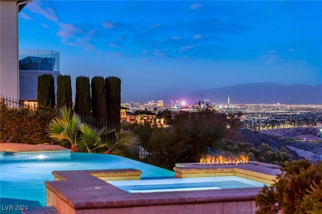 pool at dusk with an in ground hot tub and a mountain view