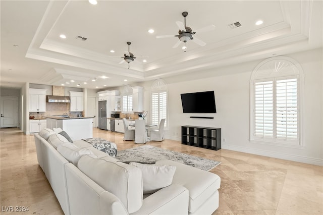 living room featuring a raised ceiling, a wealth of natural light, and ceiling fan