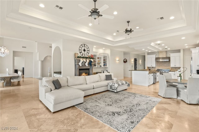 living room featuring a tray ceiling, ceiling fan, and crown molding