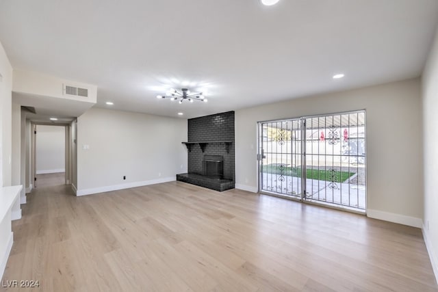 unfurnished living room featuring light wood-type flooring and a brick fireplace