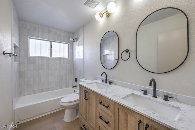 full bathroom with hardwood / wood-style floors, vanity, toilet, and tiled shower / bath