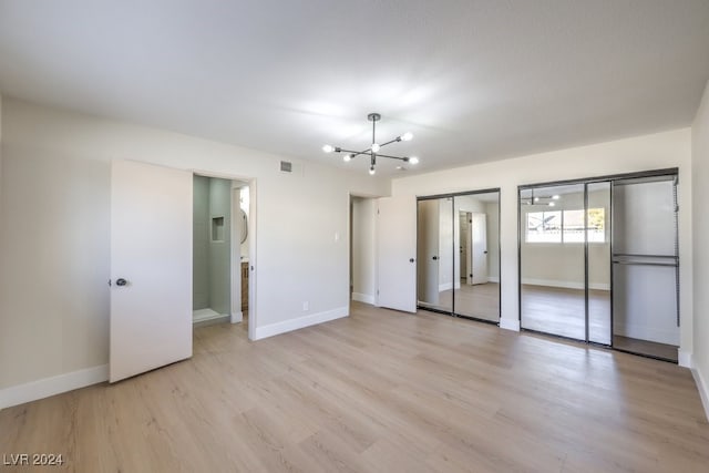 spare room featuring light hardwood / wood-style floors and an inviting chandelier