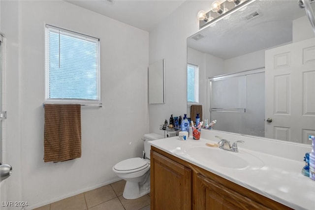 bathroom with tile patterned floors, a shower with door, vanity, and toilet