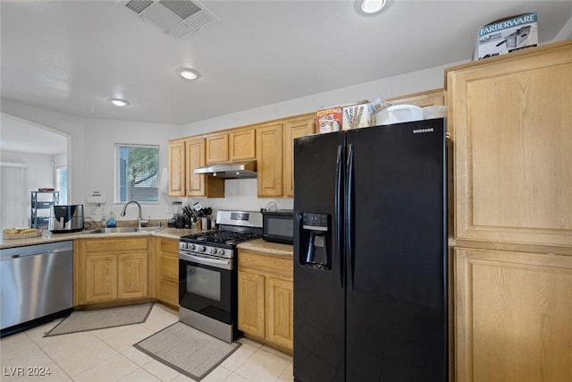 kitchen featuring black appliances, light brown cabinets, light tile patterned floors, and sink