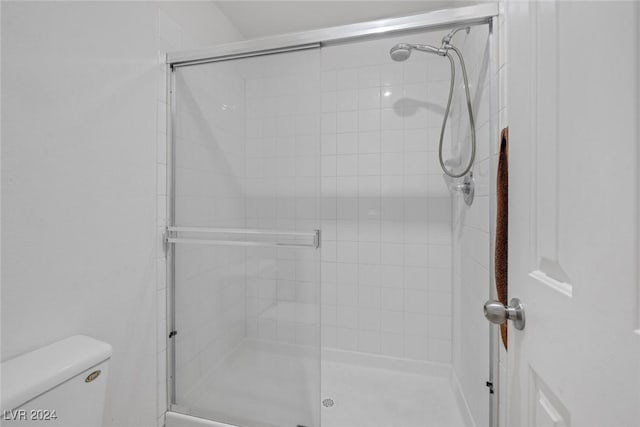 bathroom featuring toilet and a shower with shower door