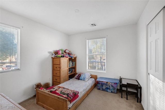 bedroom with light colored carpet and multiple windows