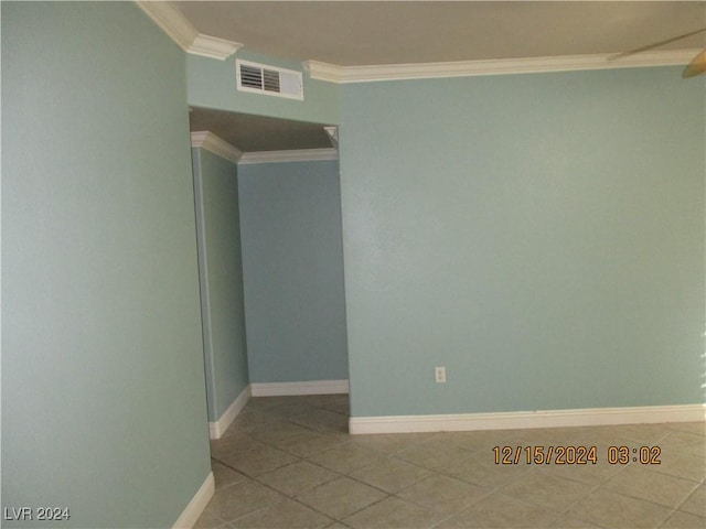 empty room featuring light tile patterned floors and crown molding