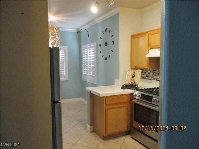 kitchen with tile countertops, backsplash, crown molding, light tile patterned floors, and appliances with stainless steel finishes