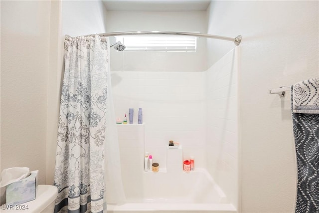 bathroom featuring shower / tub combo and toilet