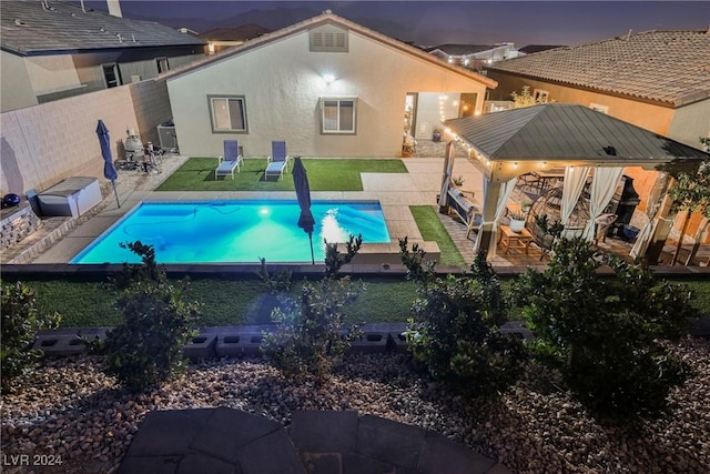 pool at dusk featuring a gazebo and a patio area