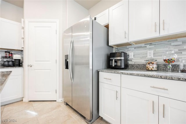 kitchen featuring light tile patterned floors, light stone counters, stainless steel fridge, decorative backsplash, and white cabinets