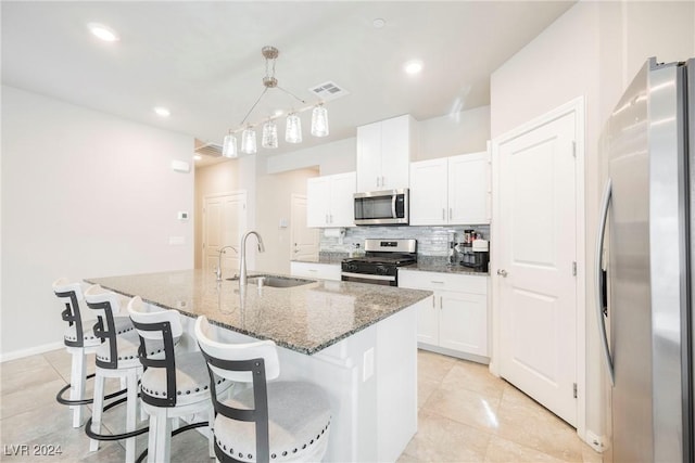 kitchen with stainless steel appliances, sink, pendant lighting, a center island with sink, and white cabinets