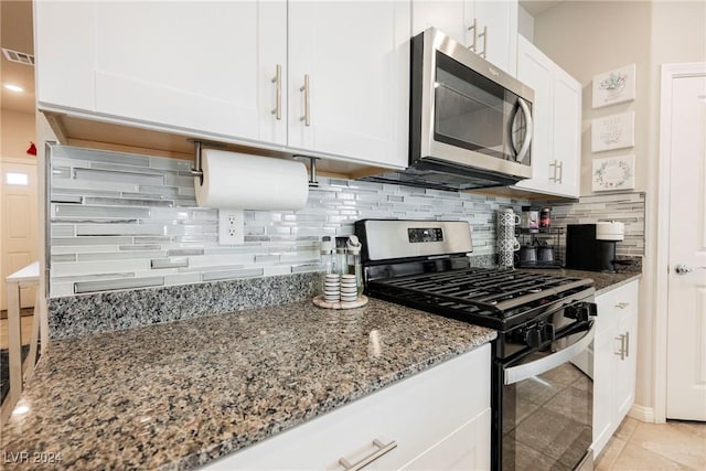 kitchen featuring white cabinets, backsplash, stone countertops, light tile patterned floors, and appliances with stainless steel finishes