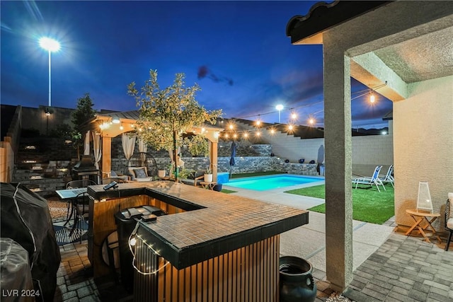 patio at twilight featuring a grill and a swimming pool with hot tub