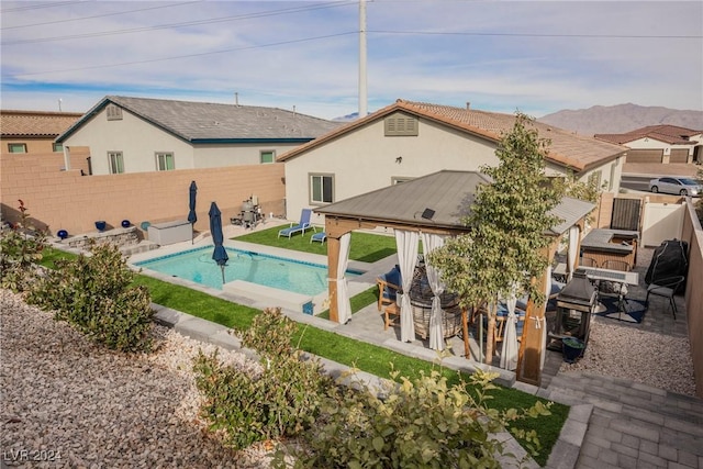 rear view of property featuring a mountain view, a patio area, and a fenced in pool