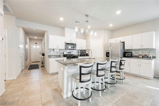 kitchen with white cabinetry, sink, stainless steel appliances, tasteful backsplash, and a kitchen island with sink