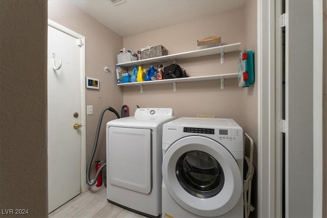 clothes washing area featuring light hardwood / wood-style floors and washer and dryer