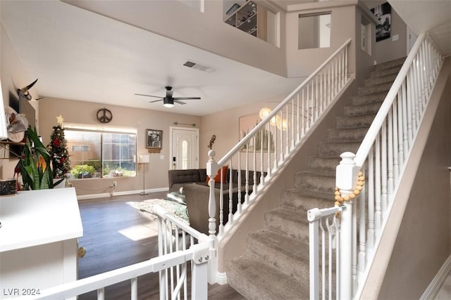 staircase featuring wood-type flooring and ceiling fan