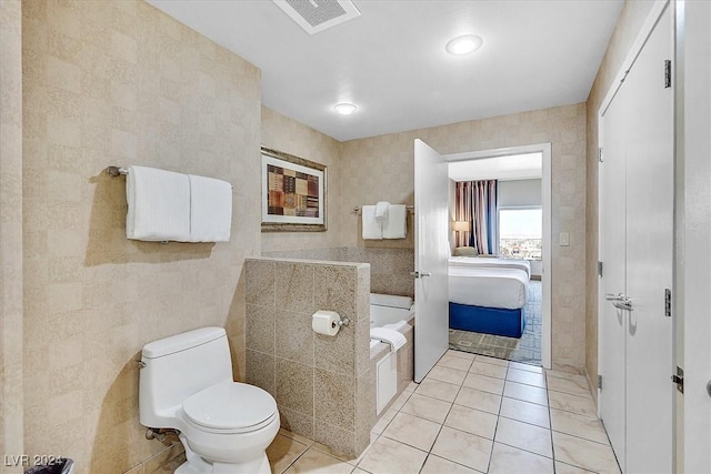 bathroom with tile patterned floors, toilet, and tile walls