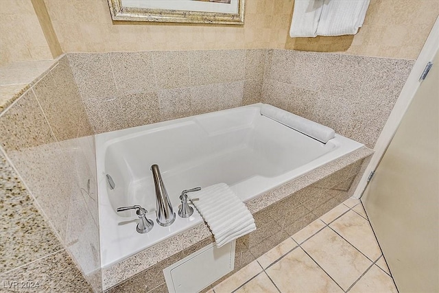 bathroom with tile patterned flooring, a relaxing tiled tub, and tile walls