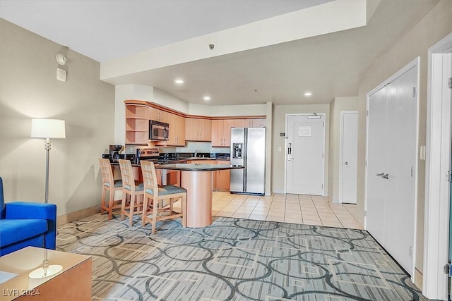 kitchen featuring sink, kitchen peninsula, a breakfast bar area, light tile patterned flooring, and appliances with stainless steel finishes