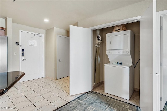 laundry room featuring light tile patterned floors and stacked washer / dryer