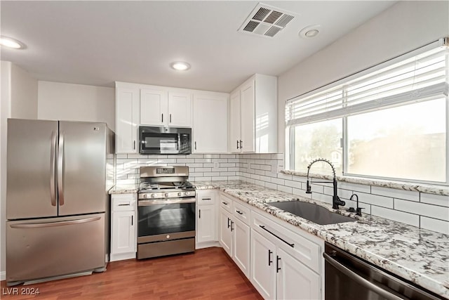 kitchen with white cabinetry, dark hardwood / wood-style flooring, stainless steel appliances, sink, and backsplash