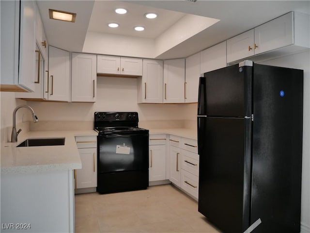 kitchen featuring white cabinets, sink, a tray ceiling, and black appliances