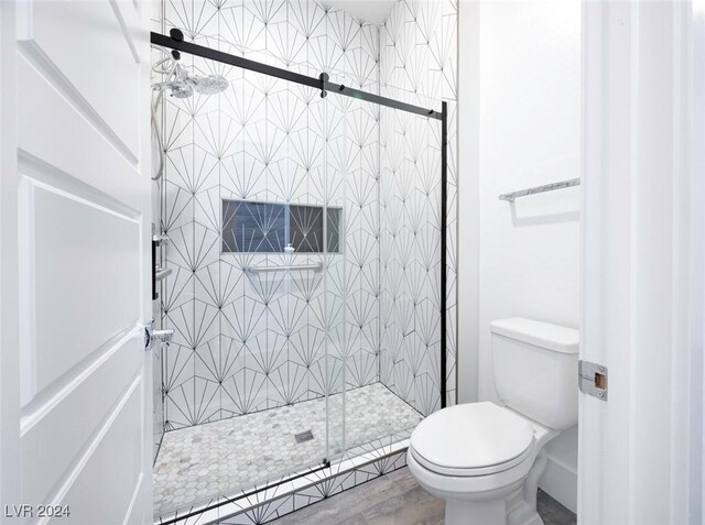 bathroom featuring hardwood / wood-style floors, a shower with shower door, and toilet