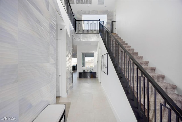 stairway featuring tile patterned flooring and a high ceiling