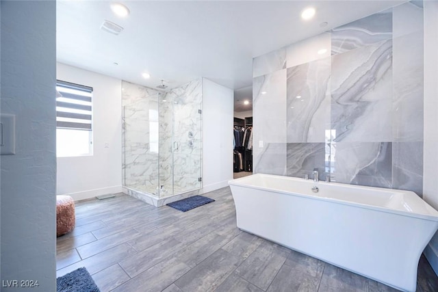 bathroom with shower with separate bathtub and tile walls