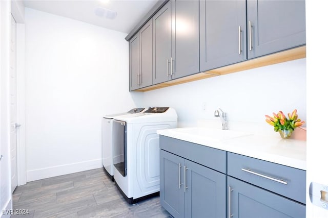 washroom with cabinets, dark hardwood / wood-style flooring, washing machine and dryer, and sink