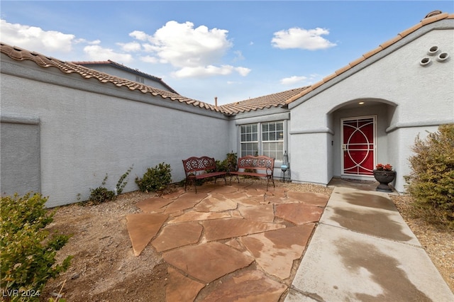 view of exterior entry with a patio area