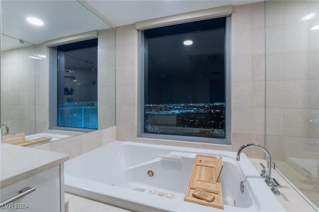 bathroom with a relaxing tiled tub, tile walls, and vanity