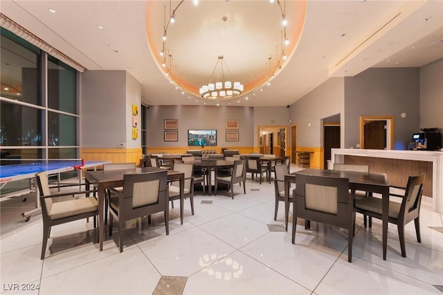 tiled dining room with a raised ceiling, a high ceiling, and a notable chandelier