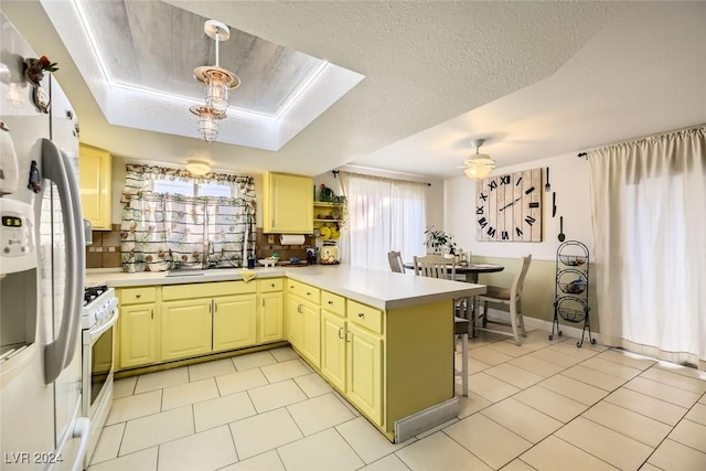 kitchen with sink, kitchen peninsula, a textured ceiling, decorative light fixtures, and white appliances