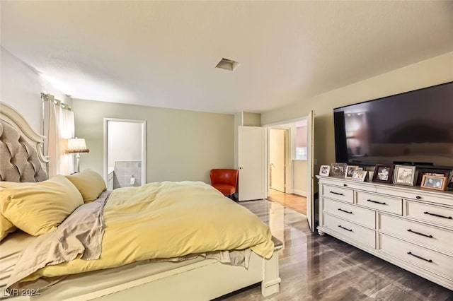 bedroom with ensuite bathroom and dark hardwood / wood-style flooring